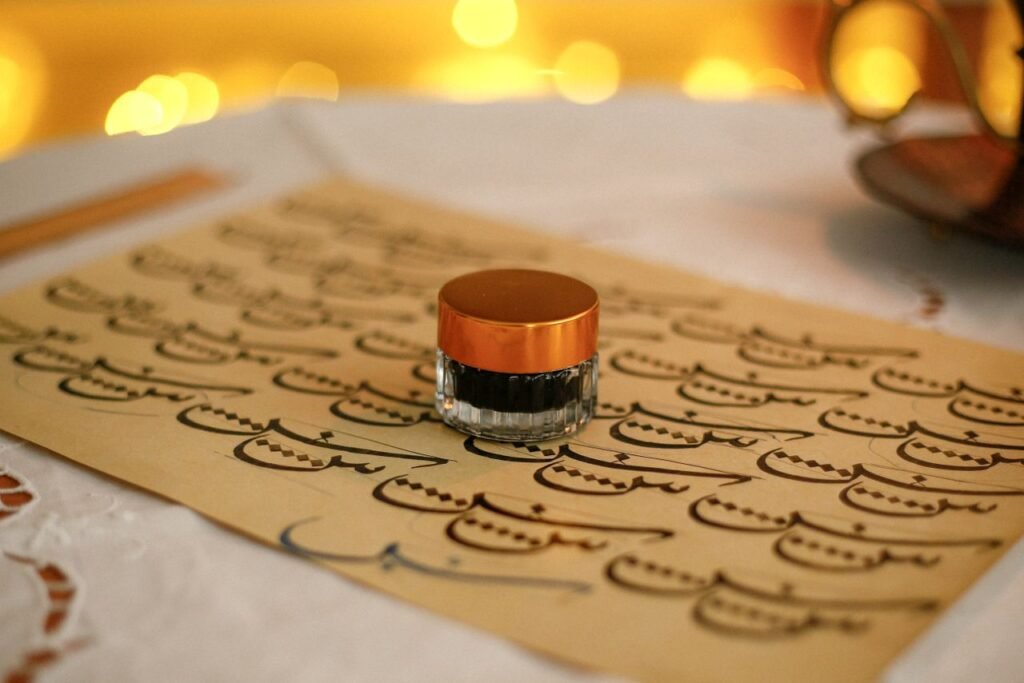 A beautifully arranged setup of Arabic calligraphy with an ink bottle on a bokeh background.
